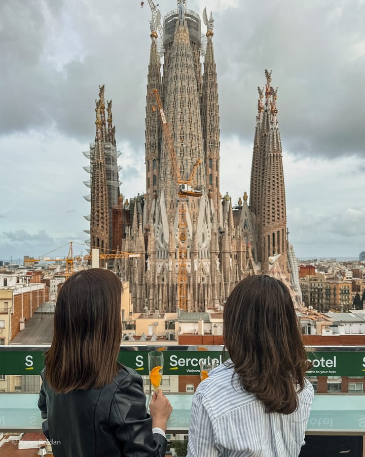Two women having drinks at the Sercotel Rosellón rooftop bar with a close-up view of the Sagrada Familia towers in the backgr
